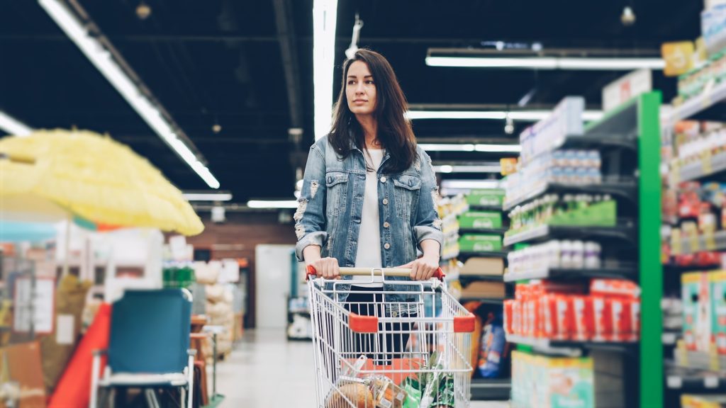 Woman shopping in a grocery store with a cart.