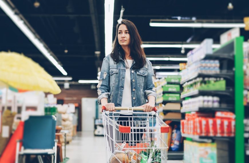Woman shopping in a grocery store with a cart.