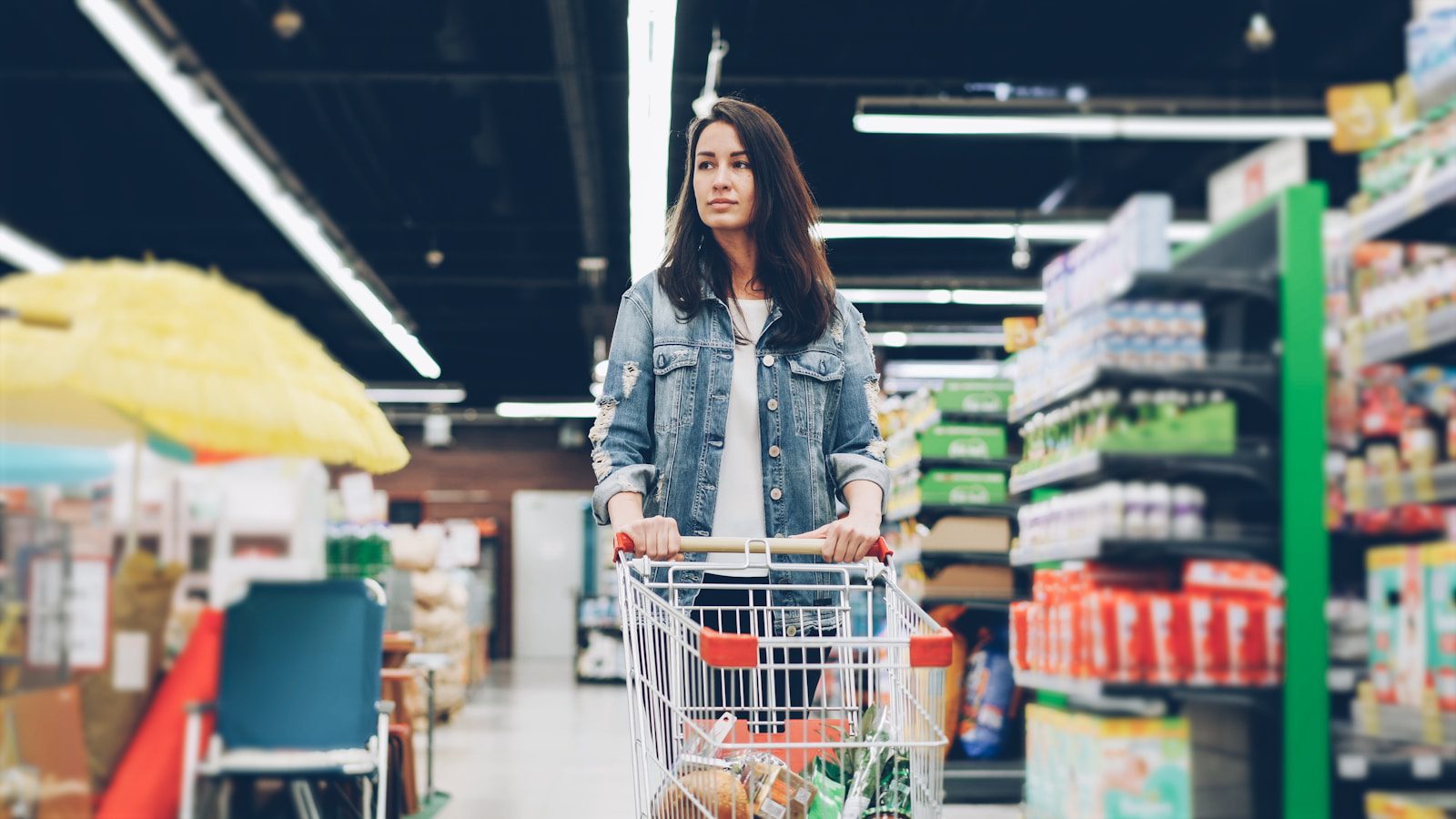 Woman shopping in a grocery store with a cart.