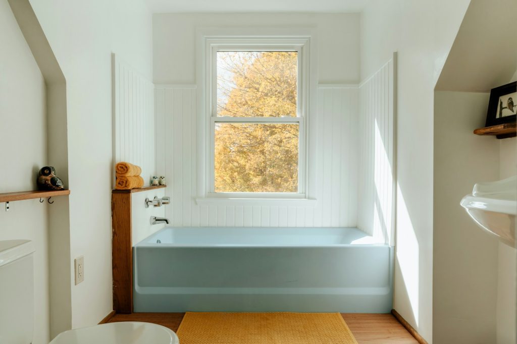 A bathroom with a tub, sink, and window