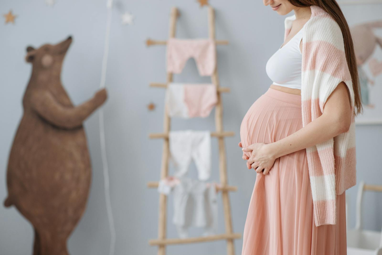 Expectant mother caressing her belly in a cozy nursery room setting, symbolizing love and anticipation.