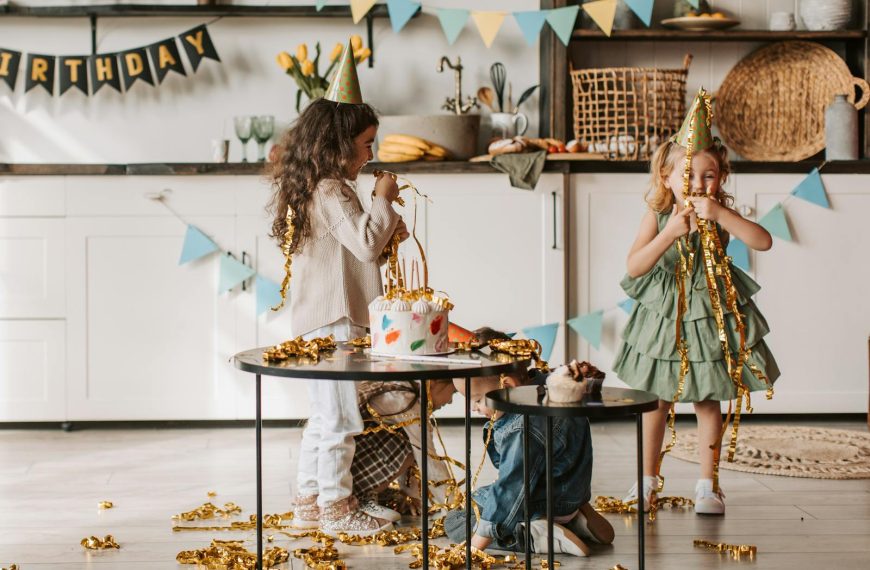 Children having fun at a birthday party with decorations and cake indoors.