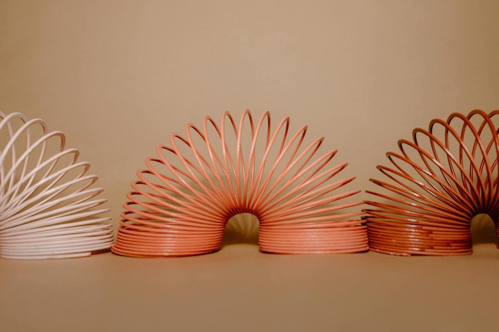 Three vibrant slinkies arranged creatively on a neutral cream background.