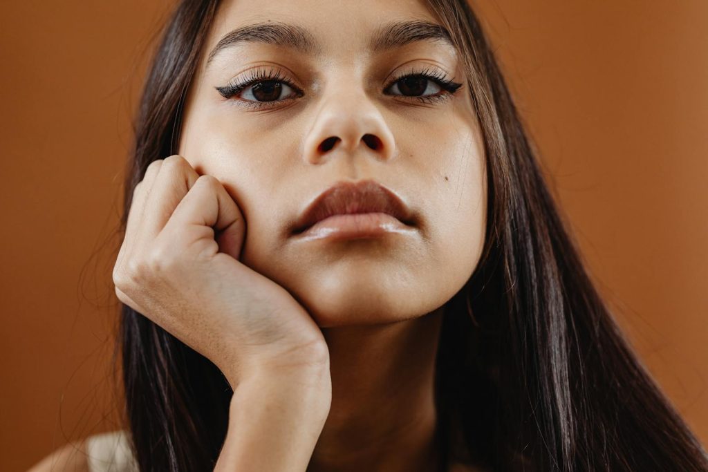 Close-up portrait of a young woman with thoughtful expression in studio setting.