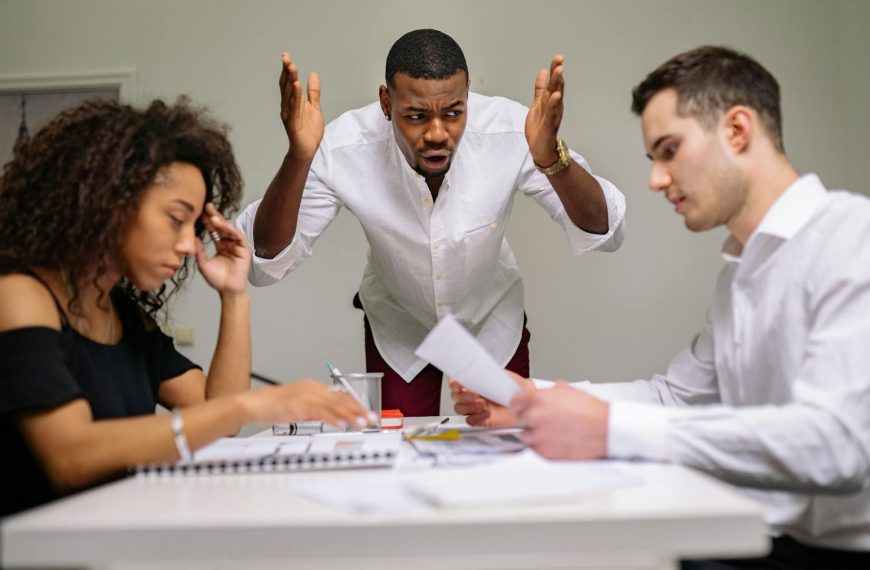 Three colleagues in a heated argument at the office, highlighting workplace stress.
