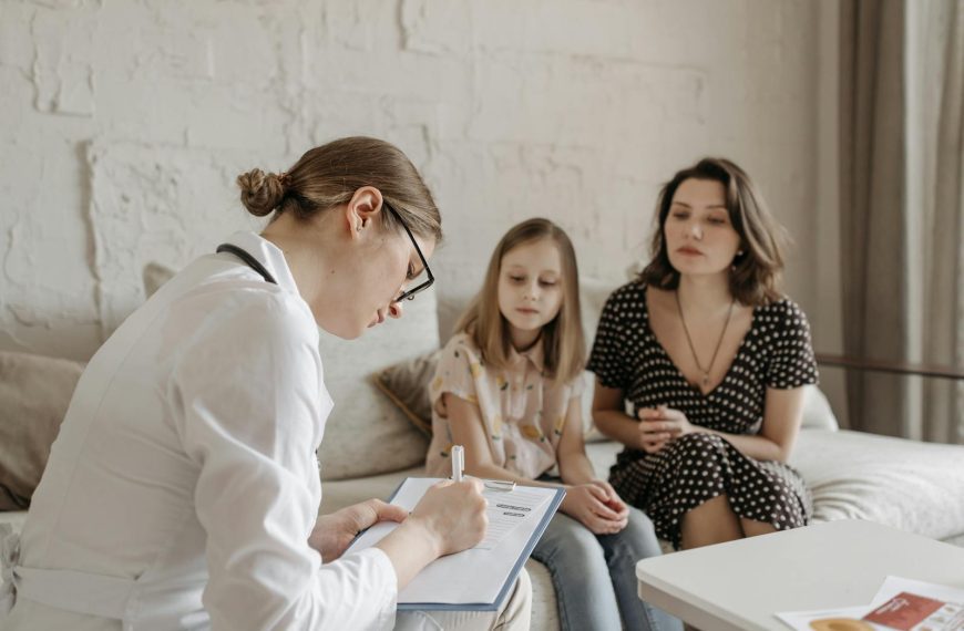 A female doctor consults with a mother and daughter inside a cozy room.