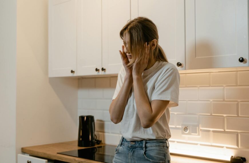 A woman in a modern kitchen looking distressed, emphasizing mental health awareness.