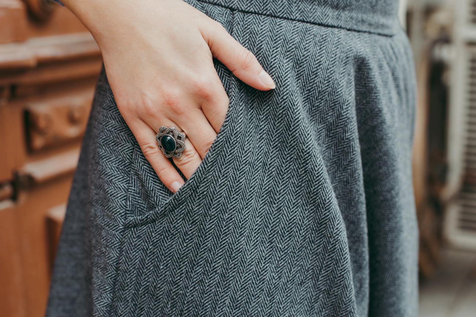 Close-up of a woman's hand with a vintage ring resting on blue tweed fabric, showcasing elegant fashion.