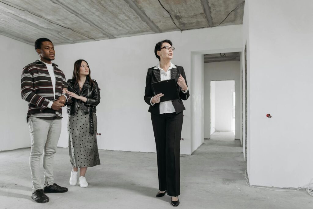 A real estate agent shows an unfinished apartment to prospective buyers.