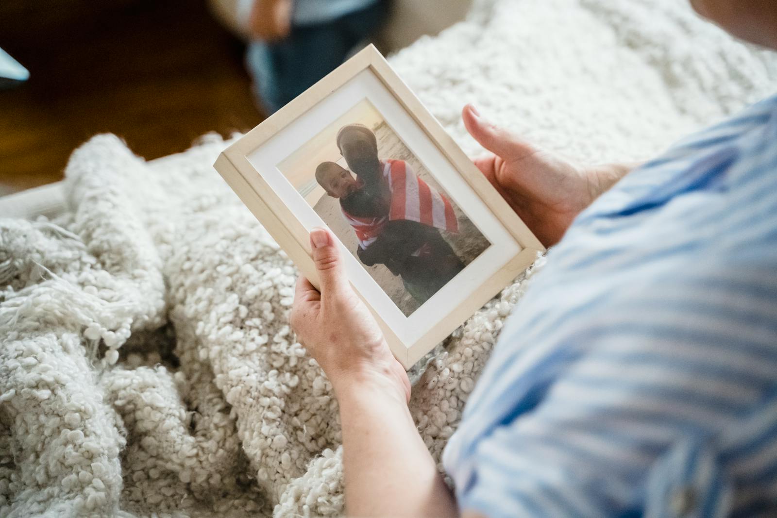 Close-up of a woman holding a cherished family photograph while relaxing on a cozy couch.