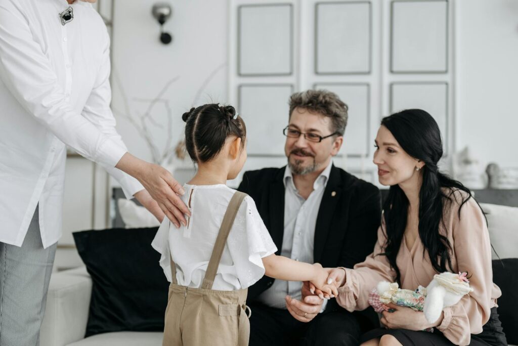 A touching moment between prospective parents and a child at an adoption center indoors.