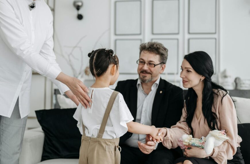 A touching moment between prospective parents and a child at an adoption center indoors.