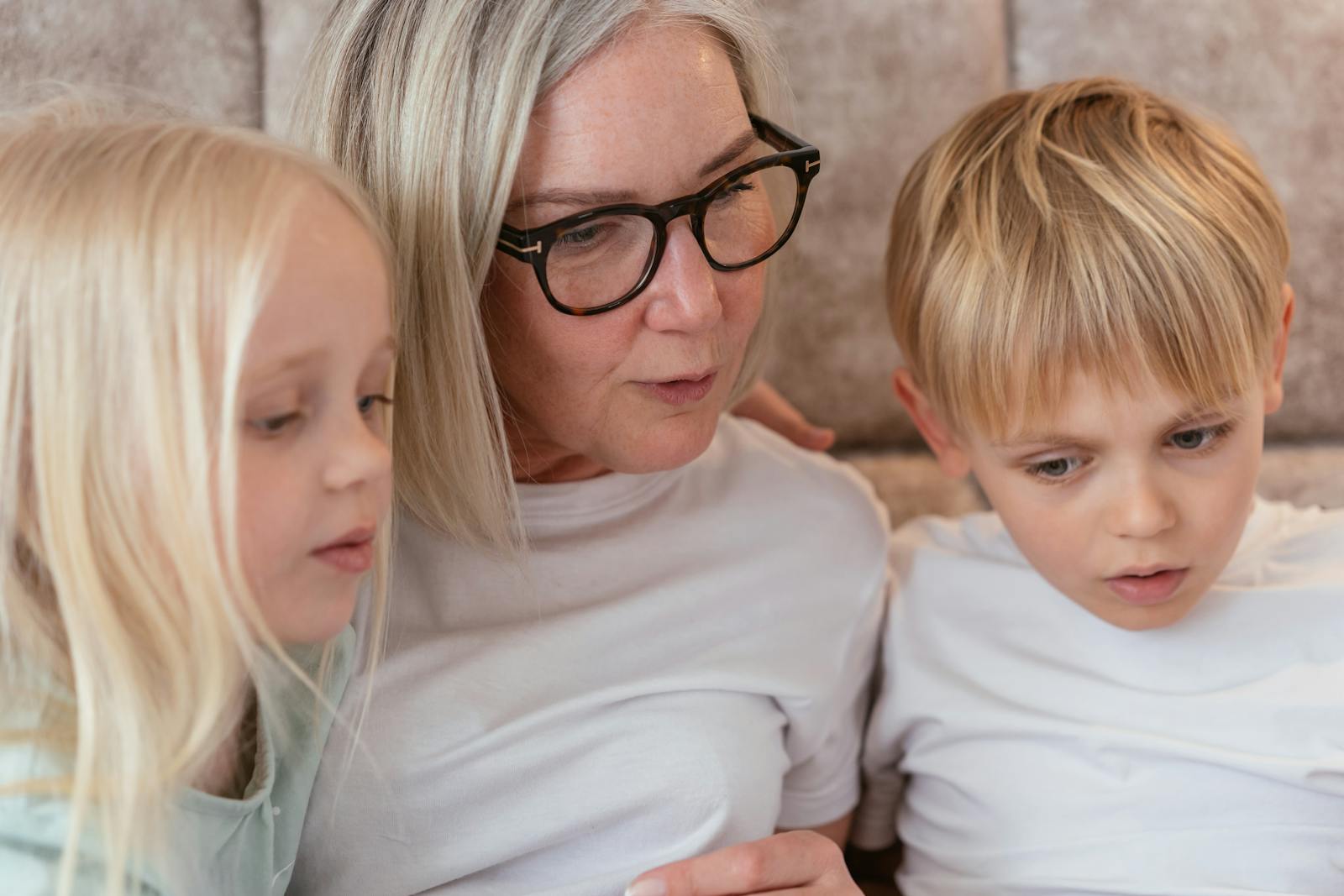A grandmother and her grandchildren enjoy quality time together indoors.