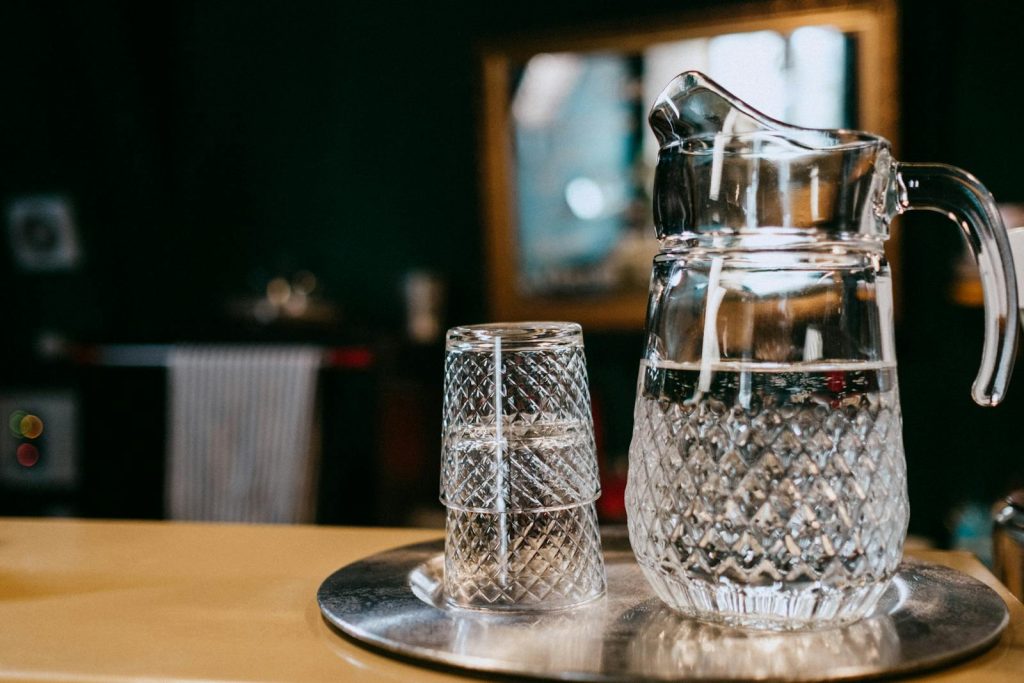 Close-up of a crystal glass pitcher and glasses with water, creating a classic still life setting.