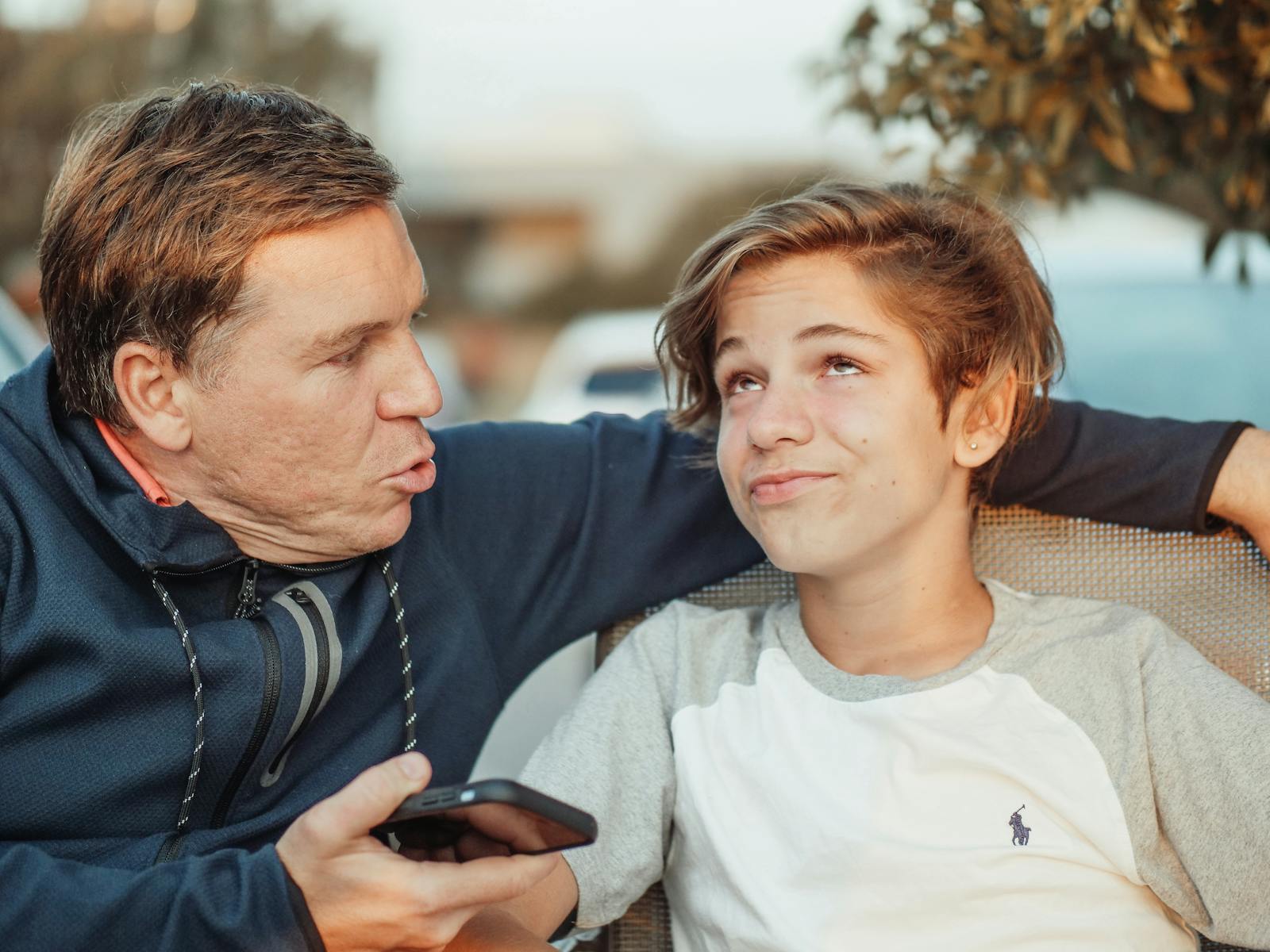 Playful interaction between father and son in a casual outdoor environment, captured in a candid moment.