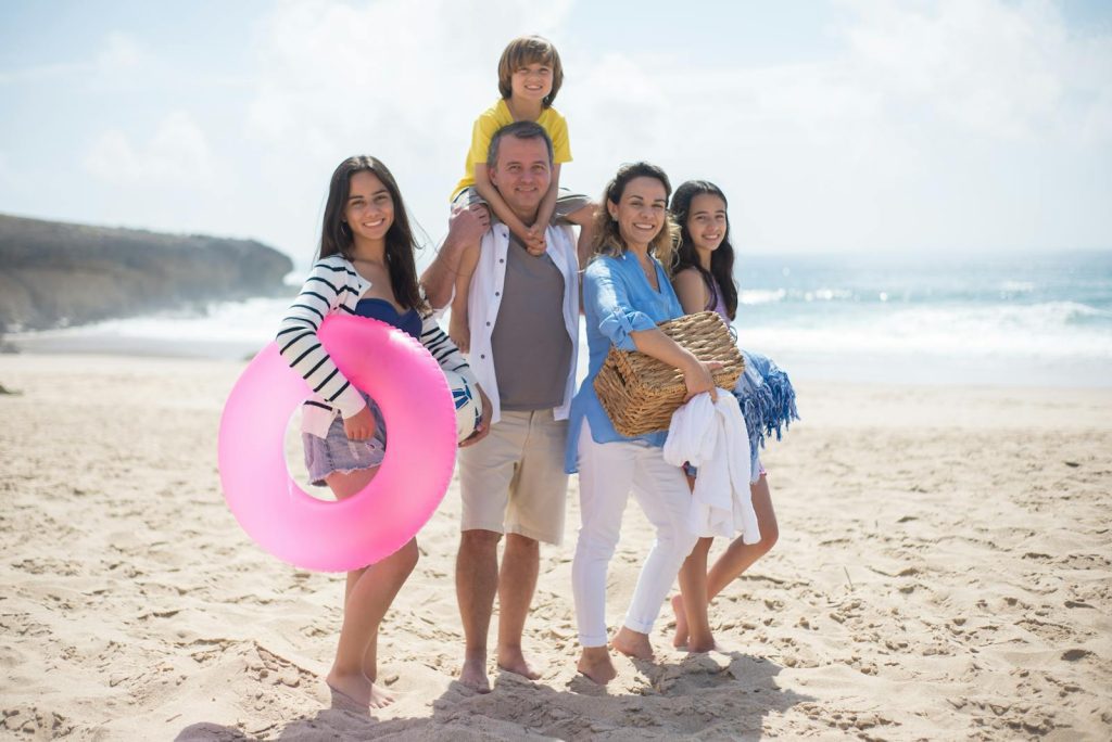 A family of five posing happily on a sunny beach in Portugal, capturing summer memories.
