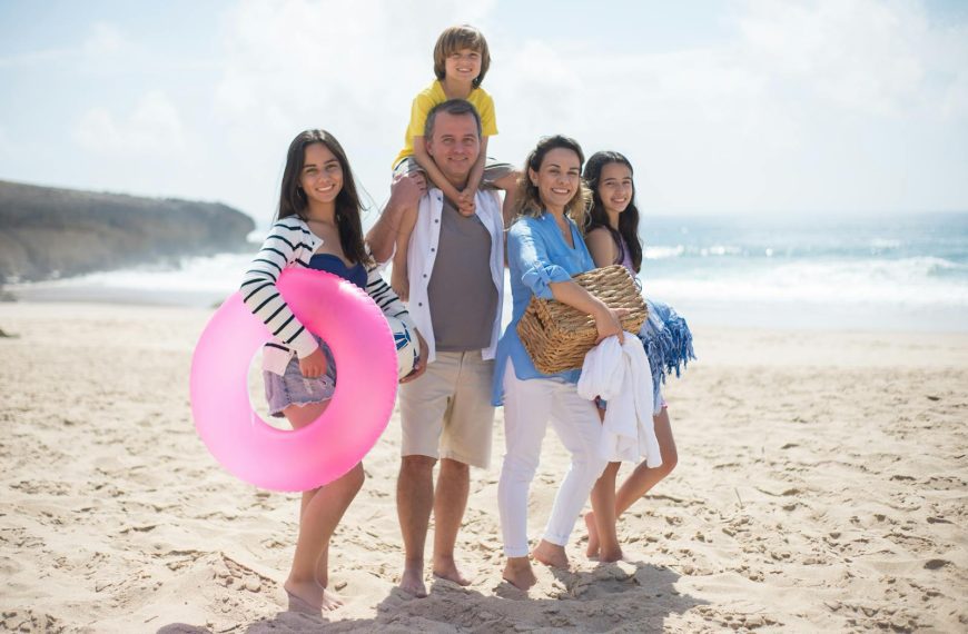 A family of five posing happily on a sunny beach in Portugal, capturing summer memories.