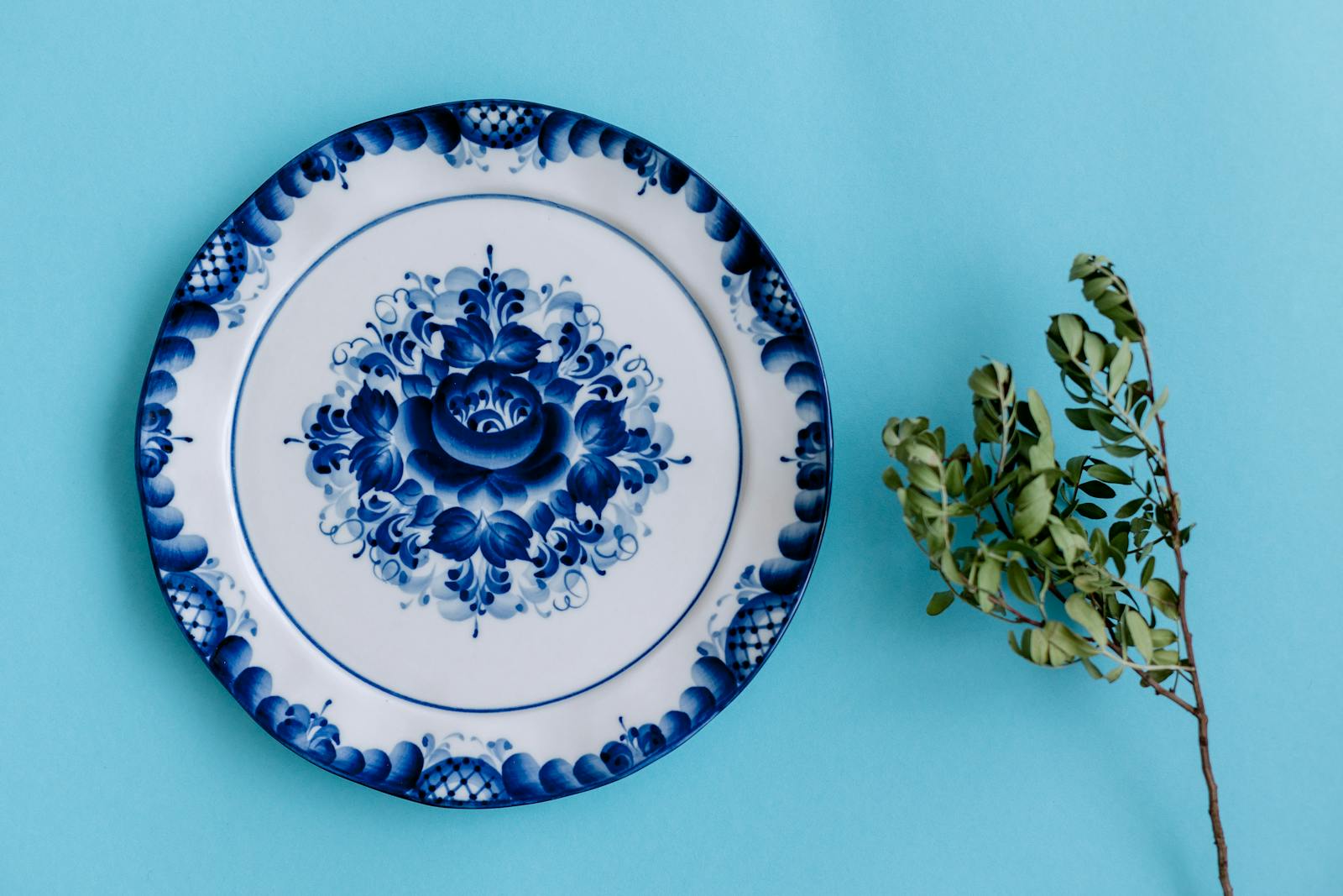 Artistic porcelain plate with intricate blue floral design on a blue background.