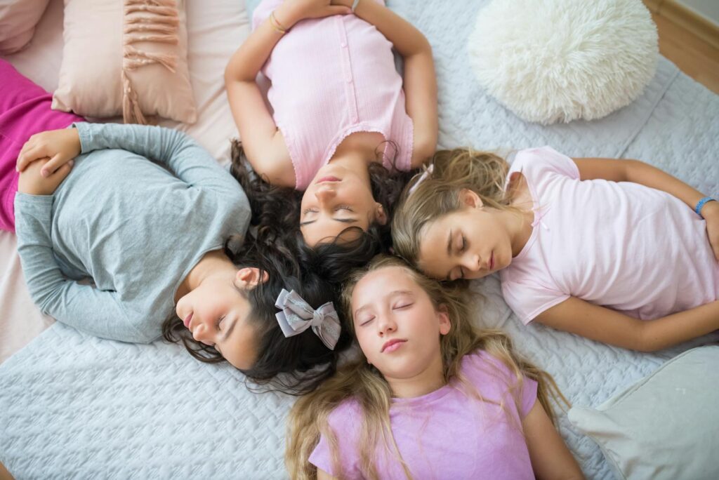 Four young girls peacefully sleeping during a fun sleepover.