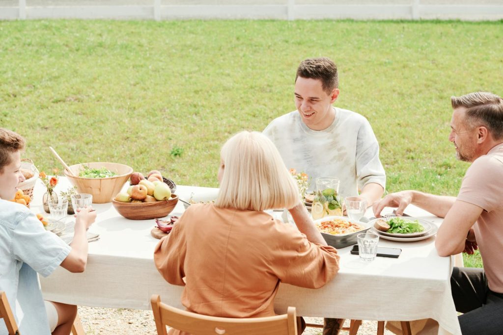 A family gathered at a table outdoors, sharing a meal and enjoying quality time together.