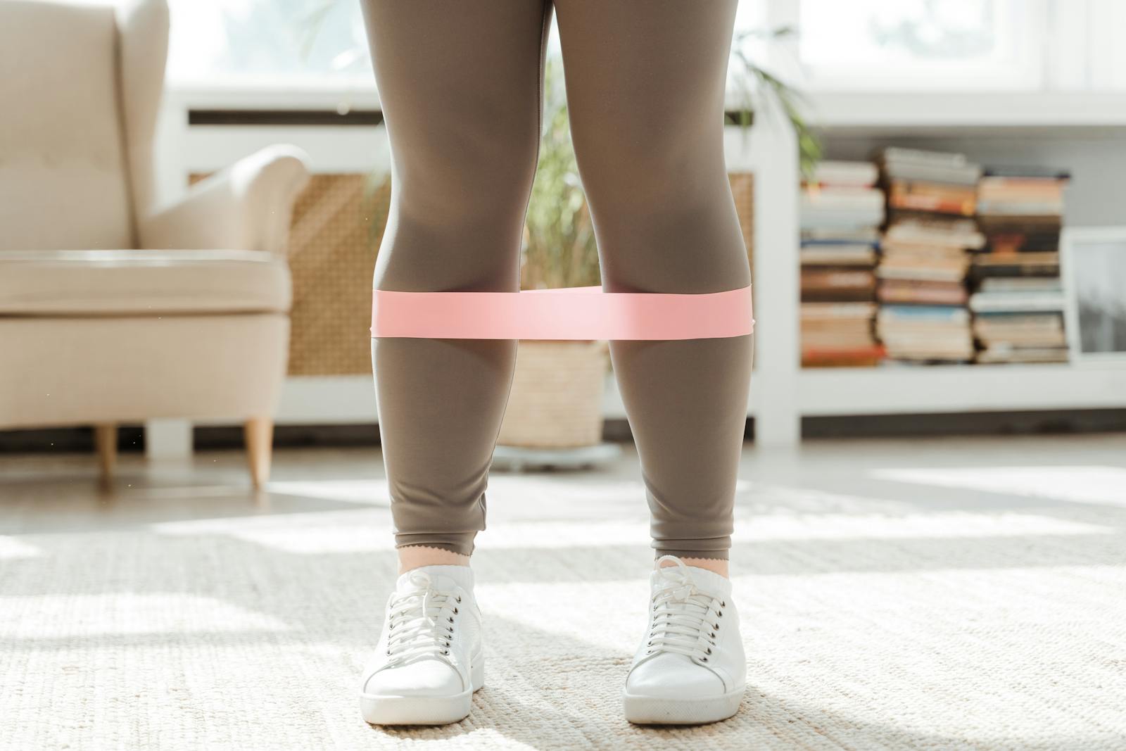 A plus-size woman working out indoors using a resistance band for fitness training.