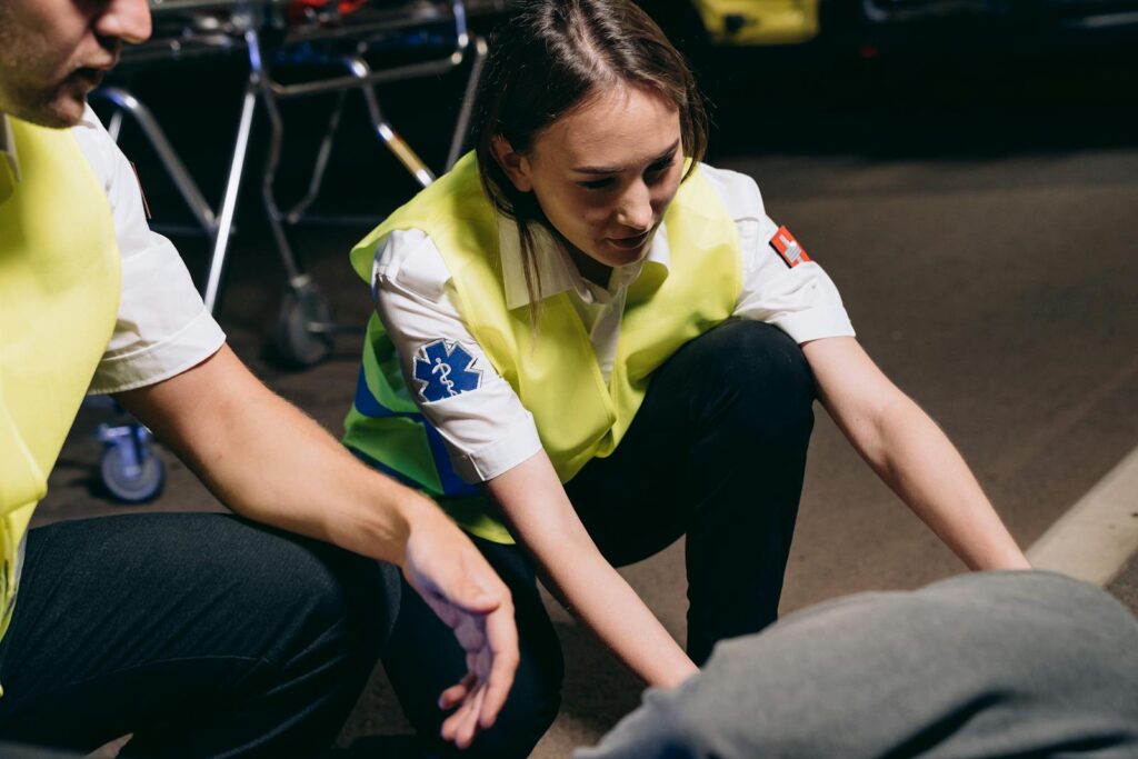 Two paramedics attend to a patient on the ground, providing emergency medical assistance.