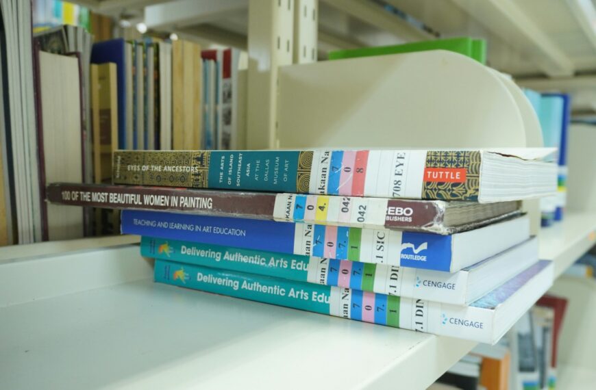 A stack of books sitting on top of a white shelf