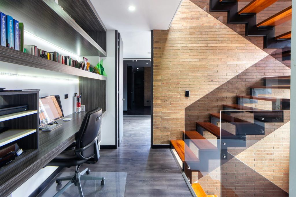 Contemporary office space featuring a sleek desk, modern design, and wooden staircase.