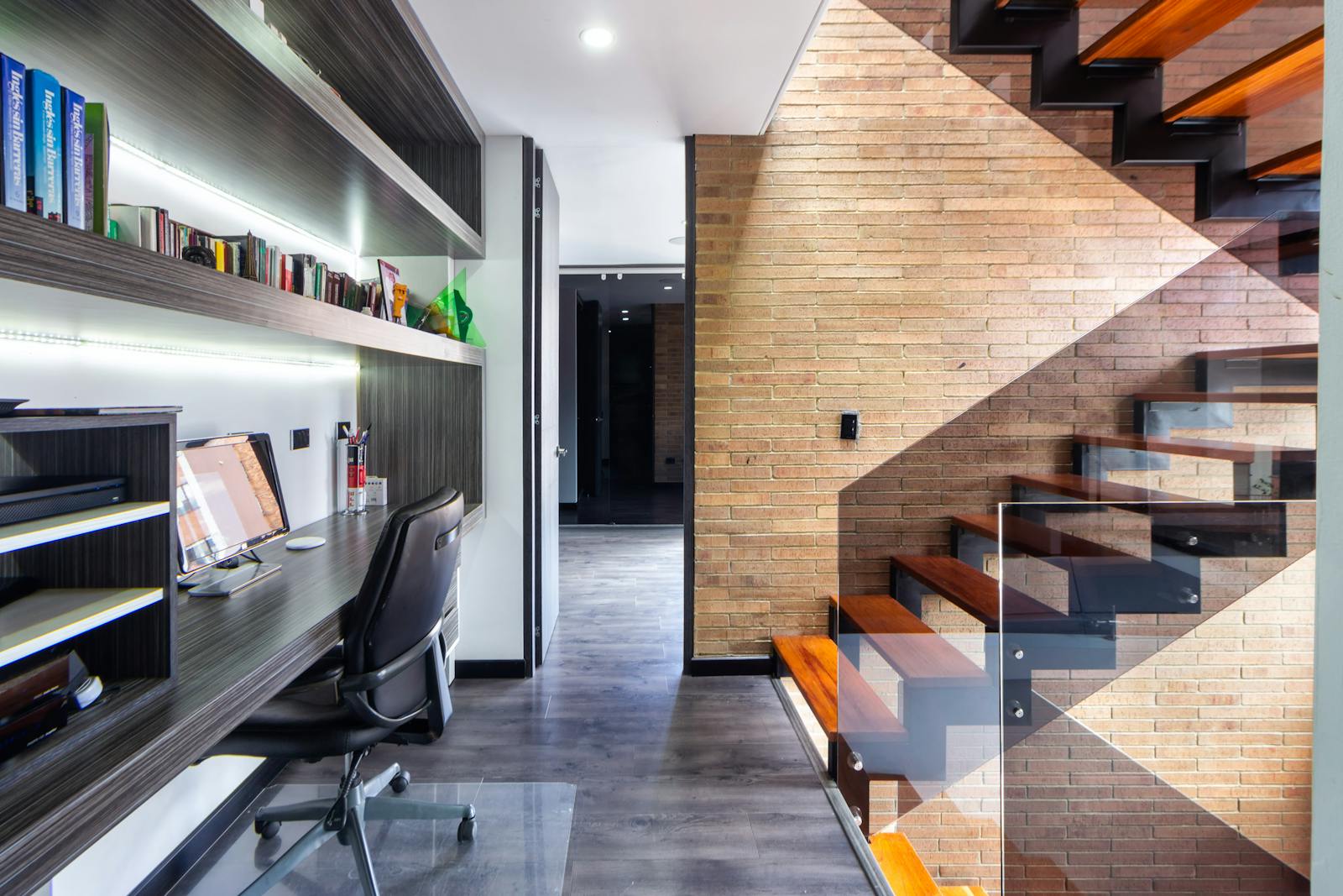 Contemporary office space featuring a sleek desk, modern design, and wooden staircase.