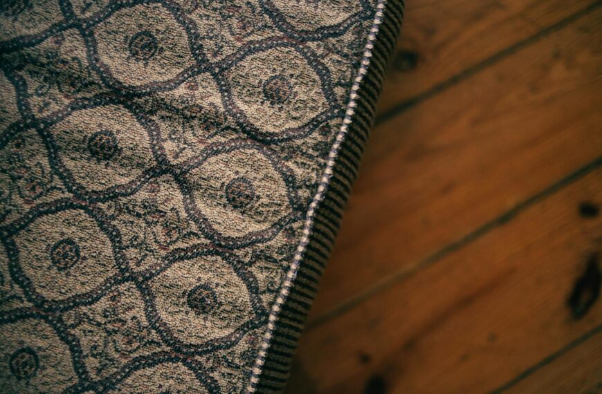 Close-up of a vintage patterned mattress corner on a wooden floor, capturing texture and style.