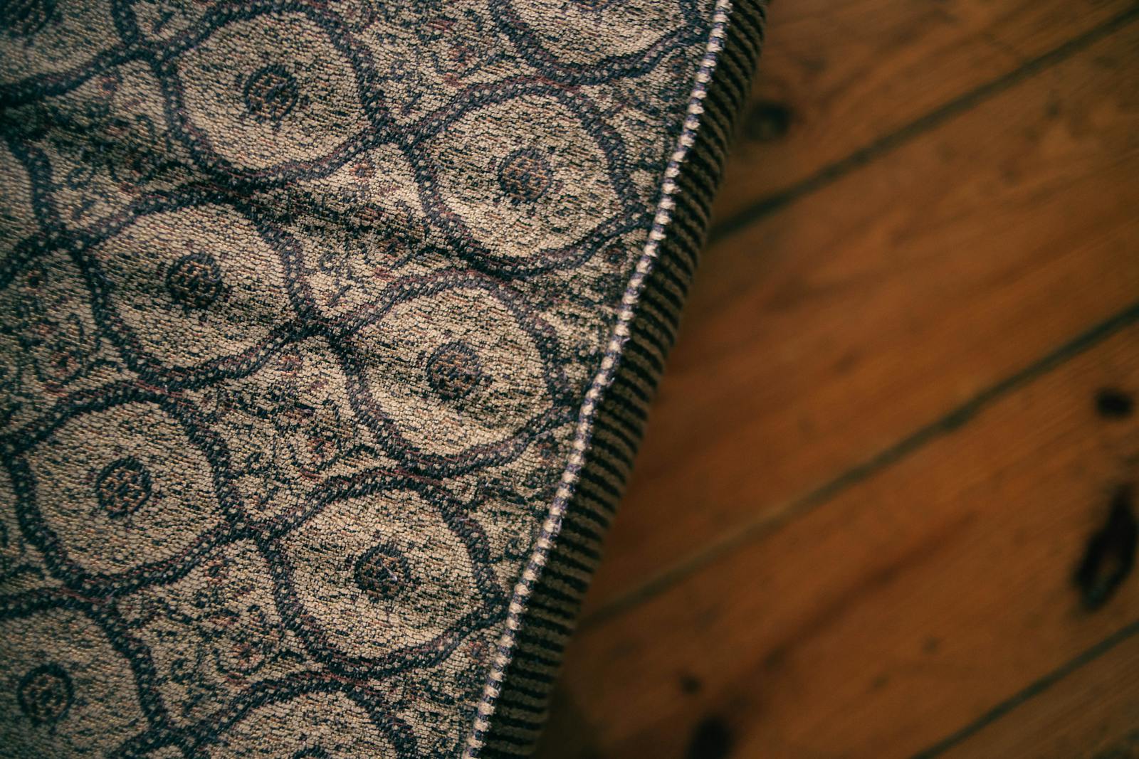Close-up of a vintage patterned mattress corner on a wooden floor, capturing texture and style.