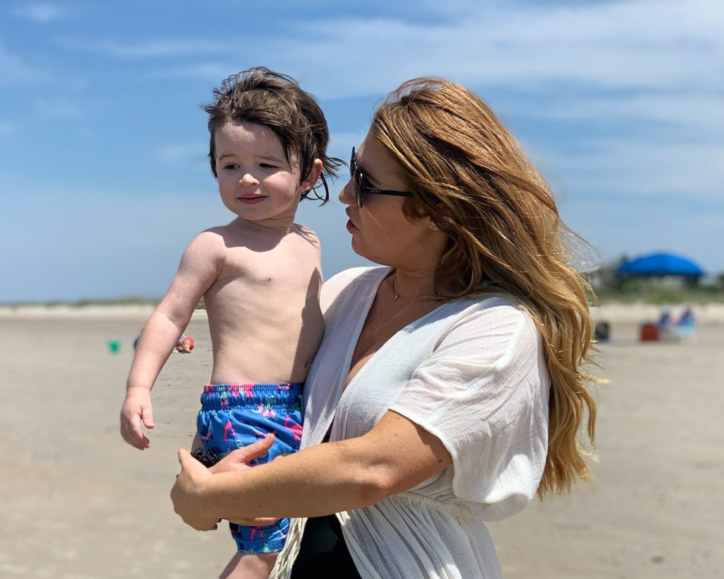woman in white shirt carrying boy in blue and white shorts