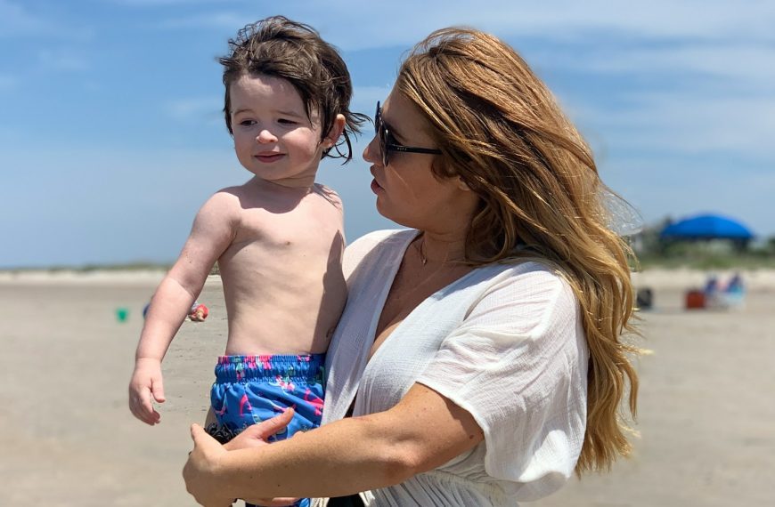 woman in white shirt carrying boy in blue and white shorts