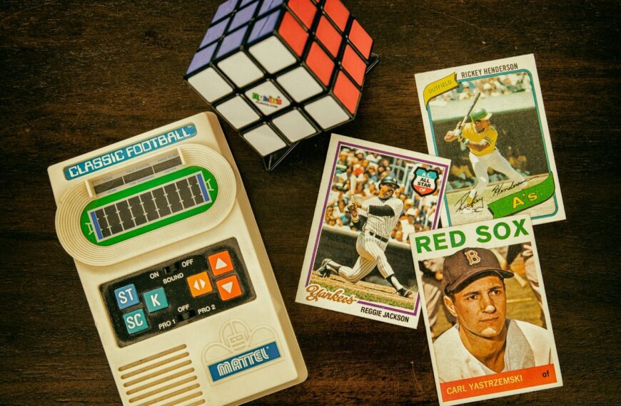 three baseball trading cards beside Rubik's cube and Classic Football handheld game console