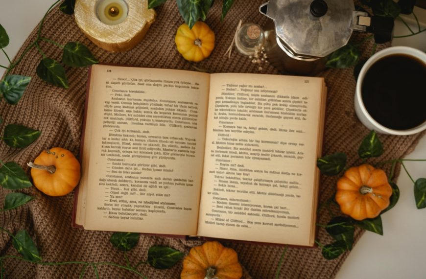 an open book sitting on top of a table next to a cup of coffee