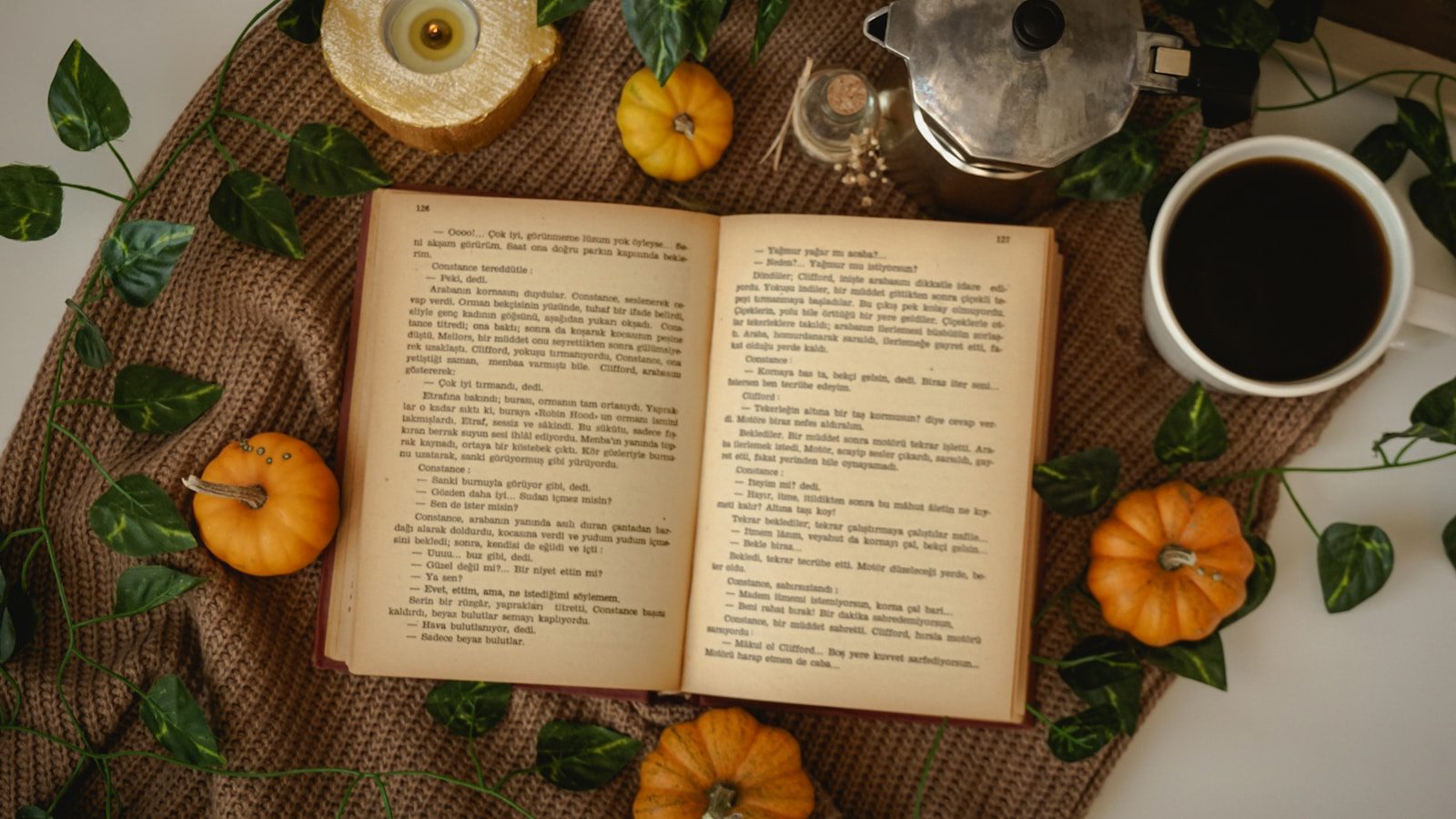 an open book sitting on top of a table next to a cup of coffee