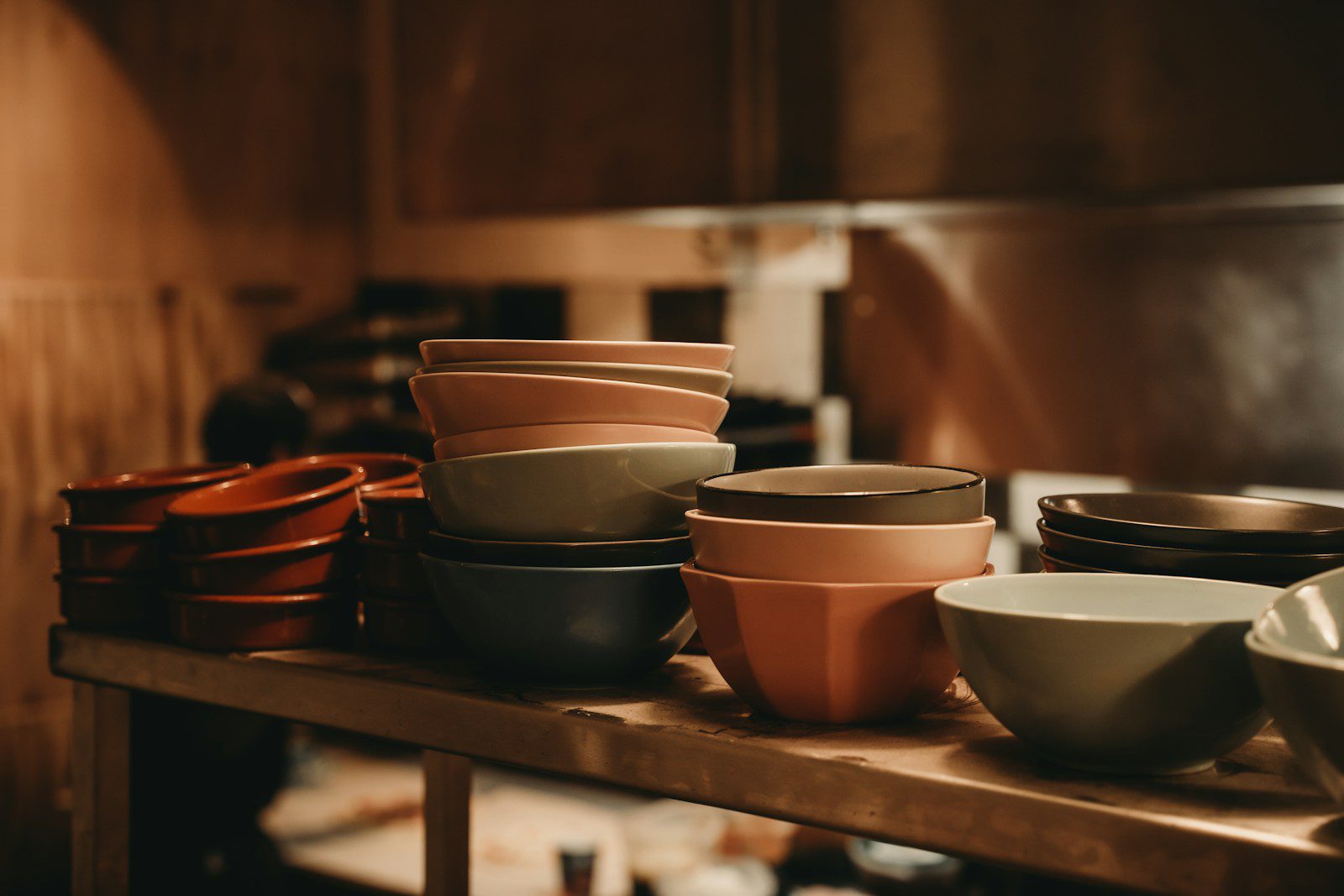 Stacks of colorful ceramic bowls on a wooden shelf.