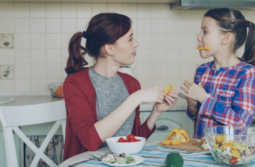 Mother and daughter enjoy snacks in the kitchen.