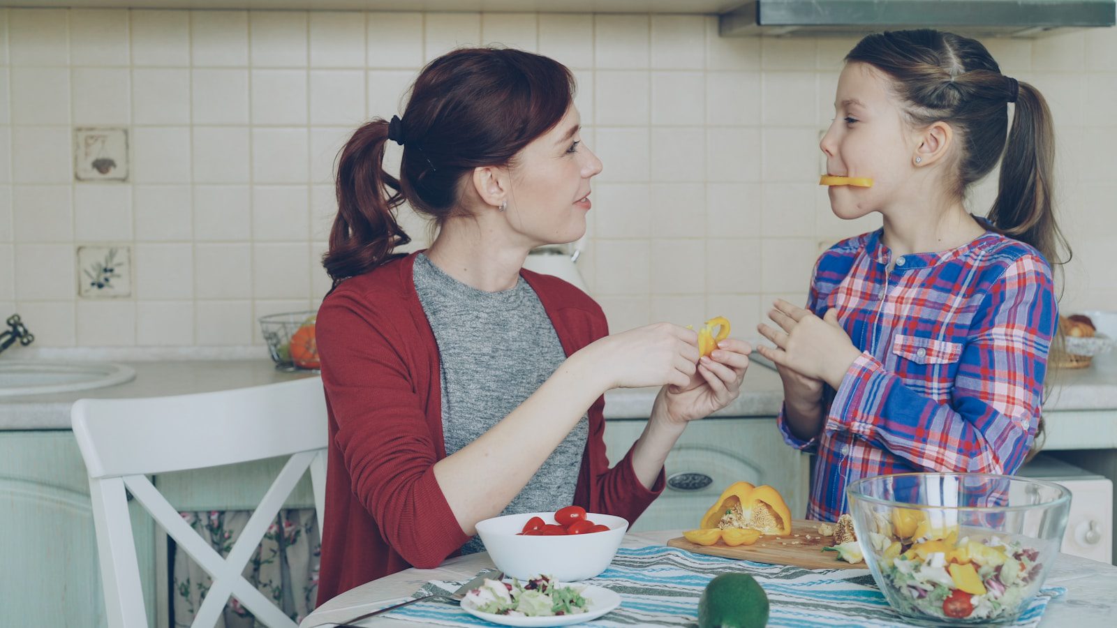 Mother and daughter enjoy snacks in the kitchen.