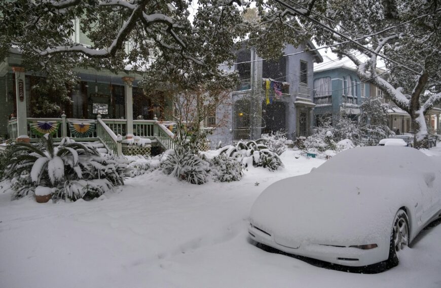 A car covered in snow parked in front of a house