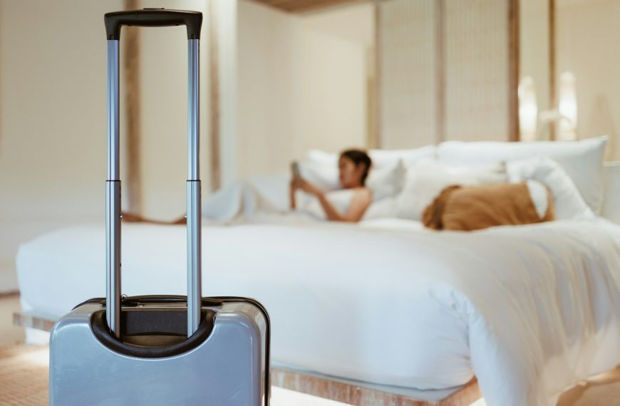 a woman laying on a bed with a suitcase in front of her
