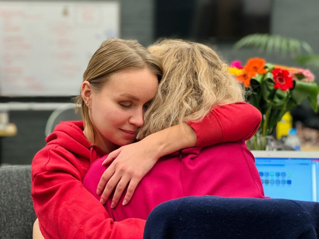 two women hugging each other in an office setting