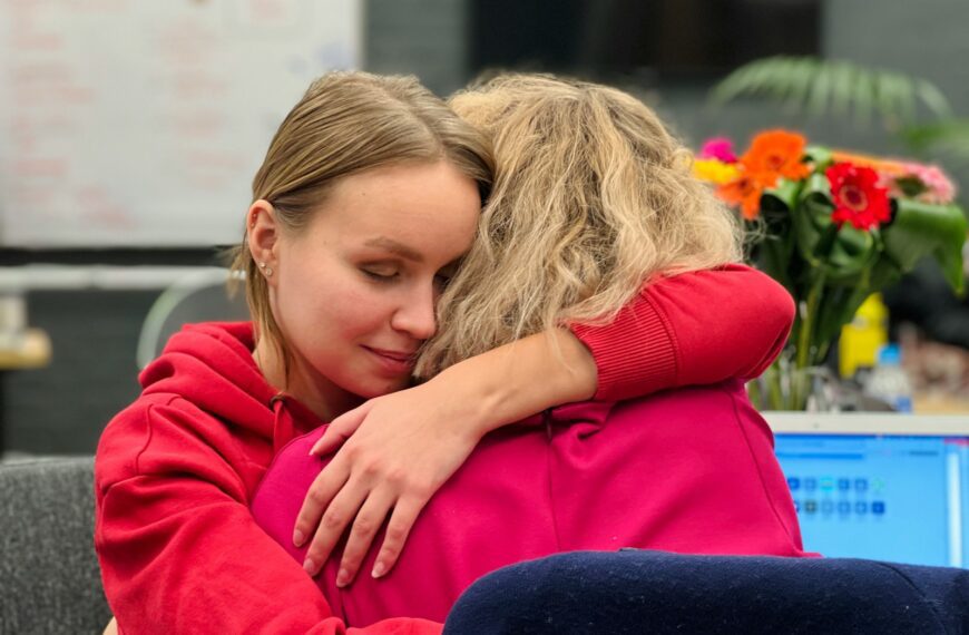two women hugging each other in an office setting