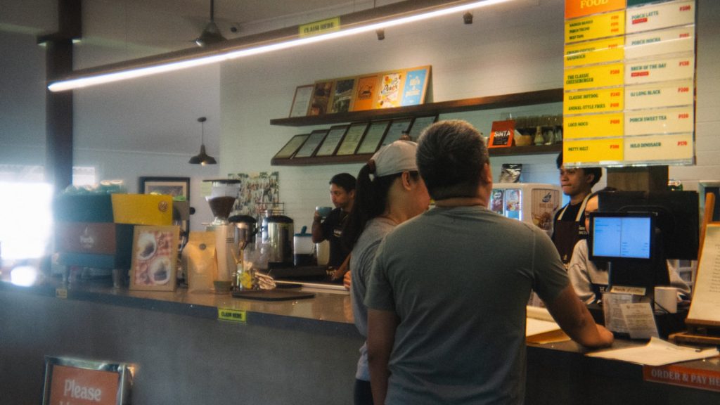 People ordering at a cafe counter with menu board