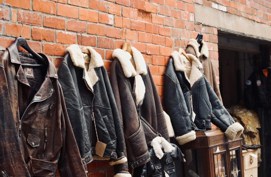four assorted leather jackets hanging on brown brick wall