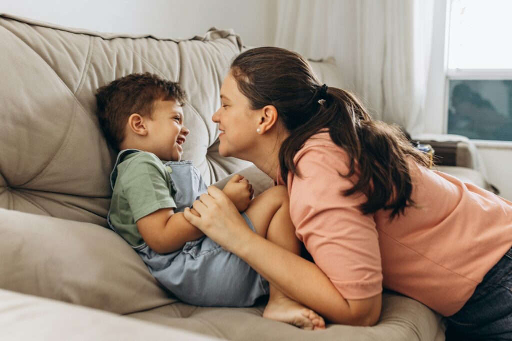 a woman and a boy are playing on a couch