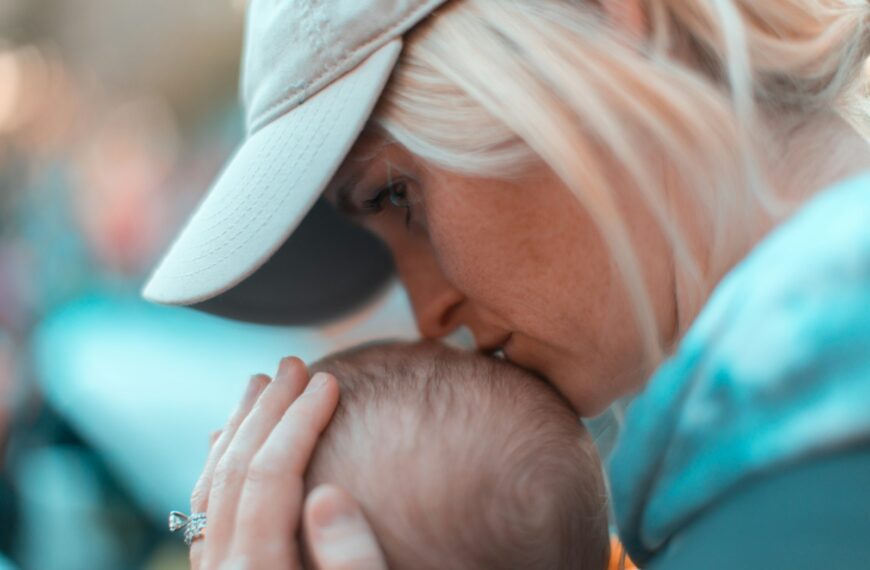 macro photography of woman kissing baby head