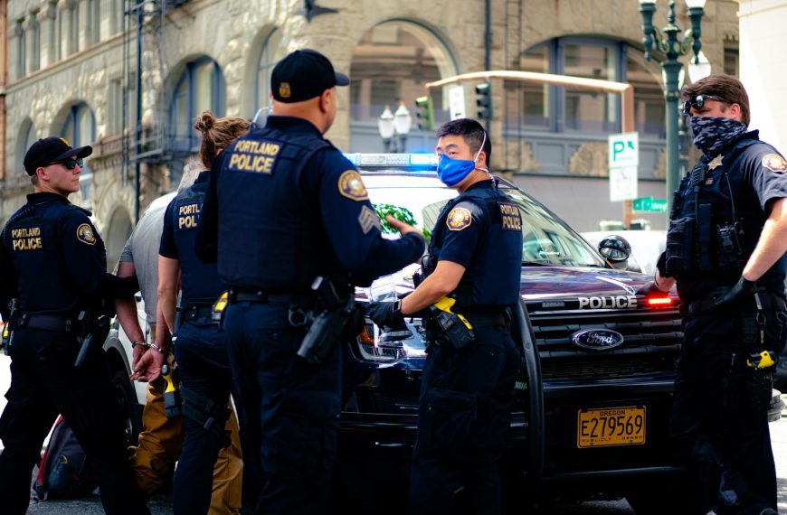 man in police uniform standing beside black car during daytime