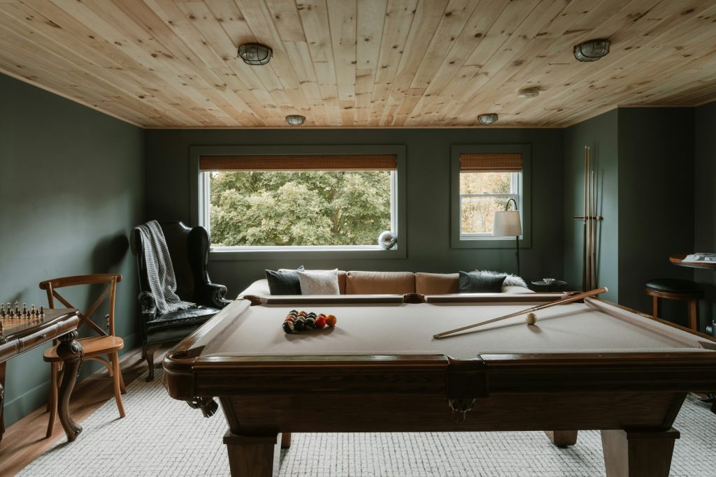 Pool table in a room with wood ceiling and sofa.