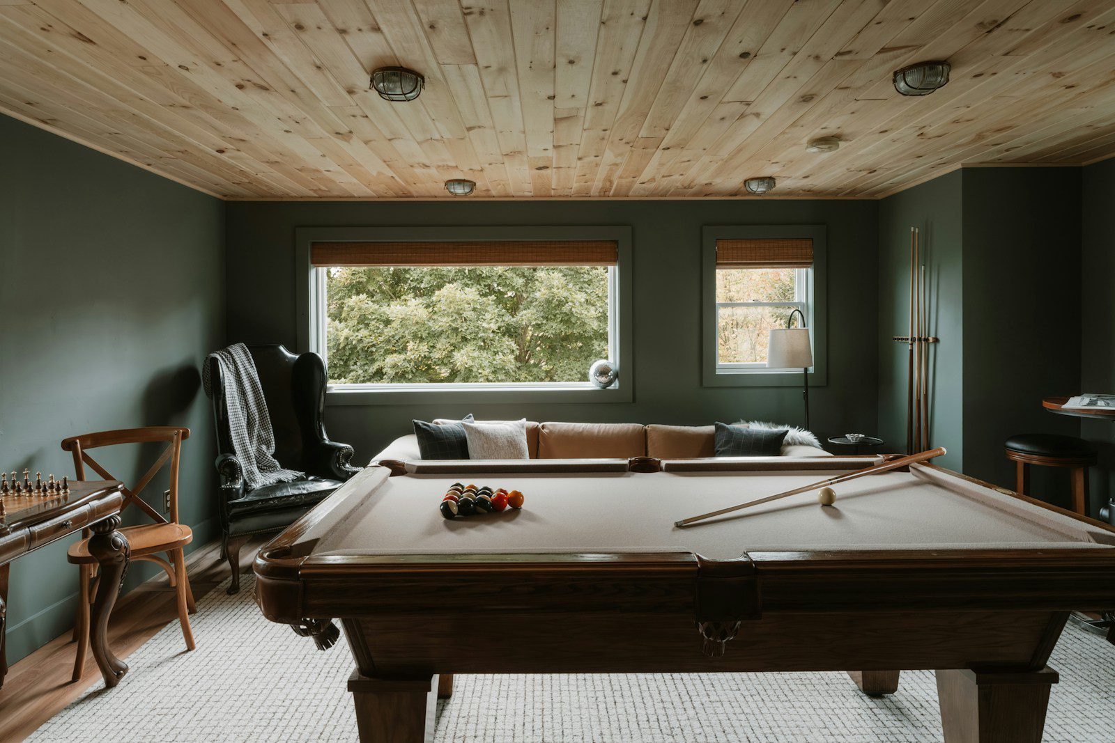 Pool table in a room with wood ceiling and sofa.